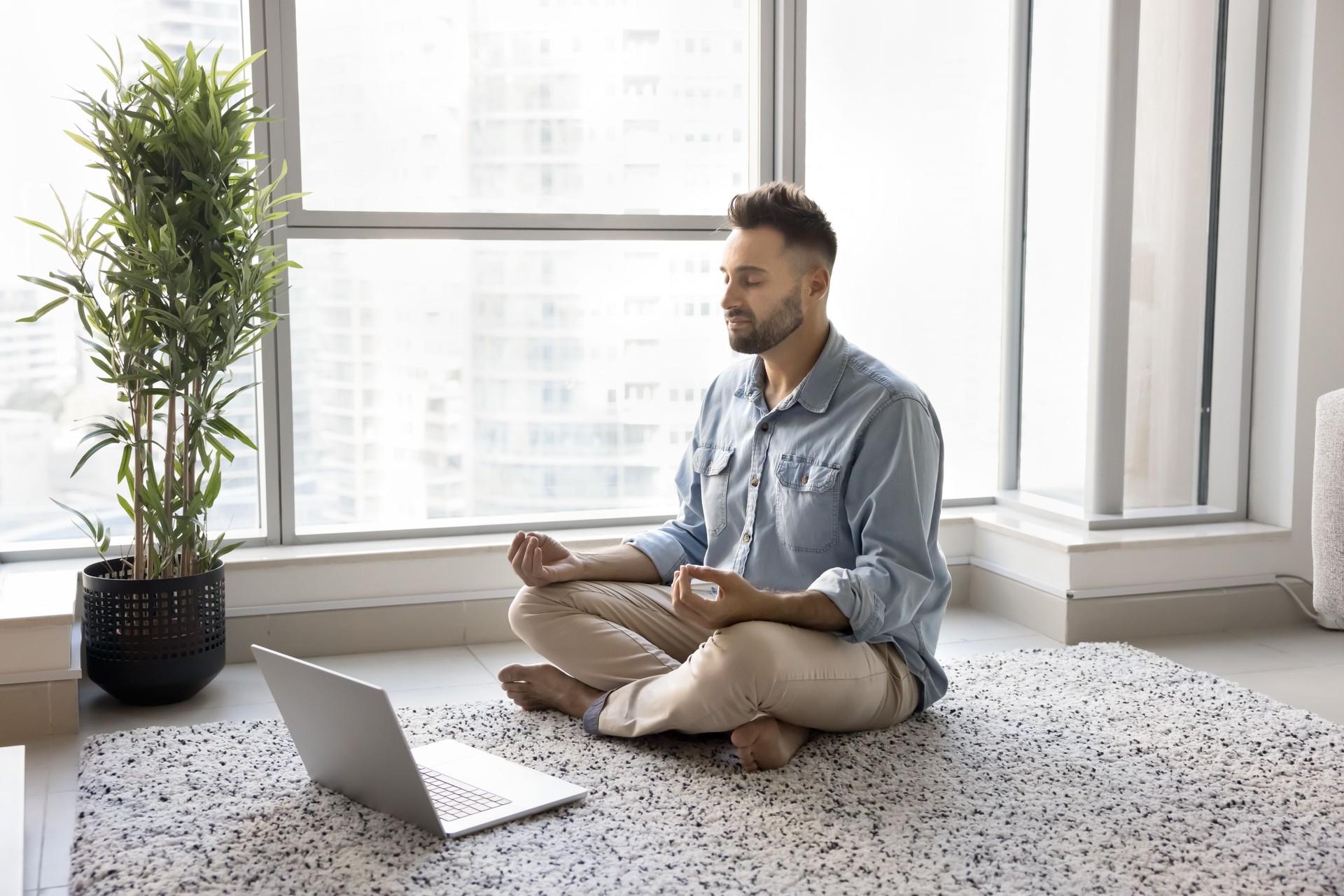 Calm concentrated young Hispanic yogi man attending online meditation class